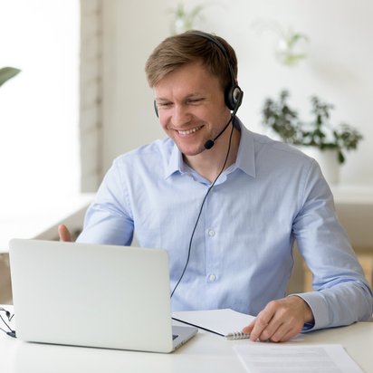 Ein Mann nimmt lächelnd an einer Videosprechstunde teil.