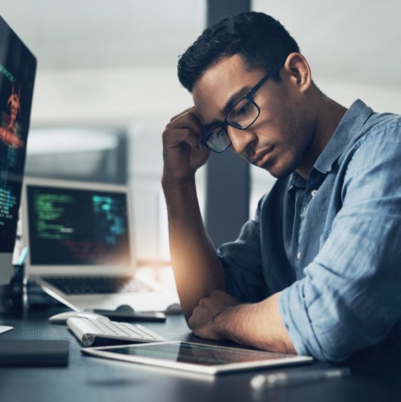 A man ponders over a tray while working at a desk
