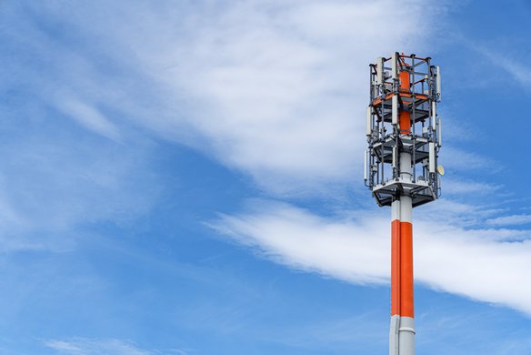 Mobilfunkmast in Rot und Weiß vor blauem Himmel. | TÜVIT