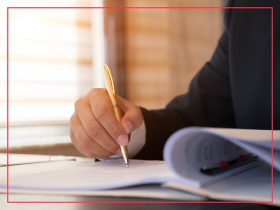 notizen-stift-unterschrift-ordner Eine Person notiert etwas in einem Ordner voller Blätter.