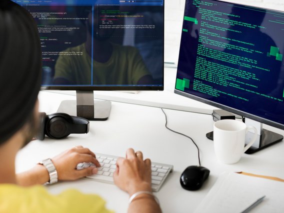 A person is working on a computer with two screens.