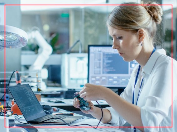 hardware-labor-arbeitssituation-cc Eine Mitarbeitende arbeitet am Schreibtisch in einem Hardware Labor.