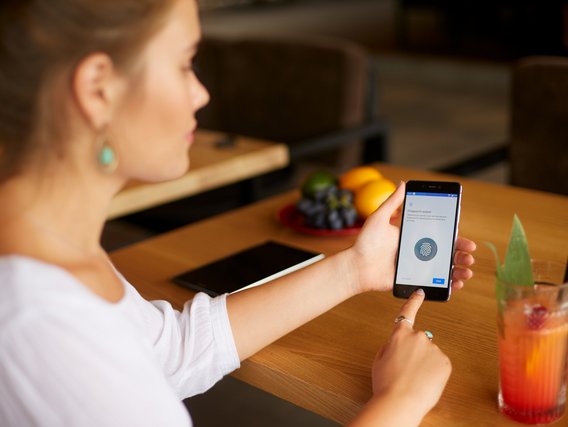 Eine Frau identifiziert sich via Fingerabdruck an ihrem Smartphone.