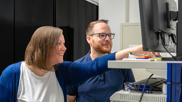 Eine Mitarbeiterin erklärt Daten eines Tests im Hardware Labor von TÜV Informationstechnik.