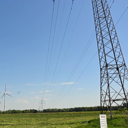 Strommast und Windräder bei gutem Wetter.