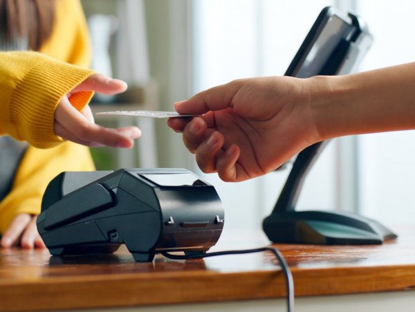 A person hands over the credit card to pay with an EC device.