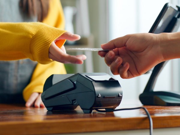 A person passes a credit card over an EC device during the payment process.