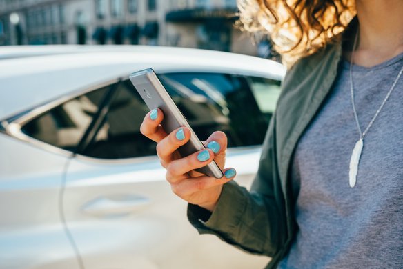 Eine Frau hält ein Smartphone in der Hand. | TÜVIT