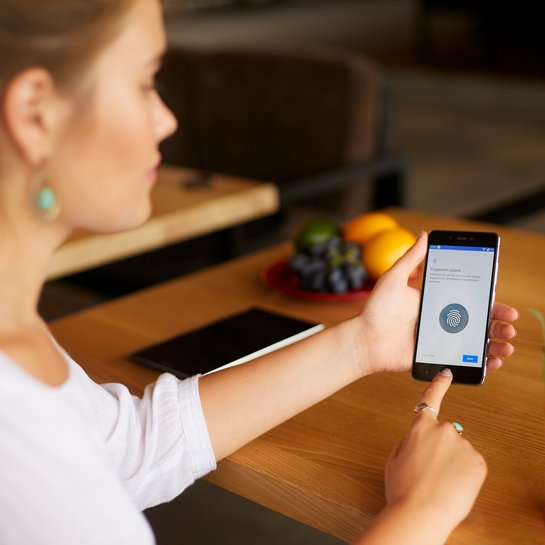 Eine Frau authentifiziert sich via Scan des Fingerabdrucks am Handy