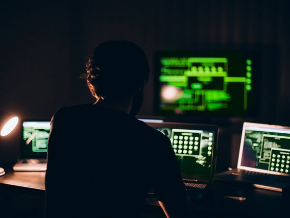 Person in a dark room at the screen.