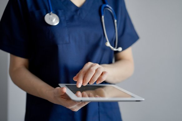 Medizinisches Fachpersonal arbeitet mit einem Tablet. | TÜVIT