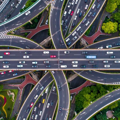 Autobahnkreuz mit vielen Fahrzeugen von oben fotografiert.