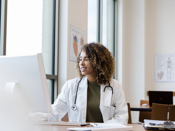 A doctor sits at a computer and works.