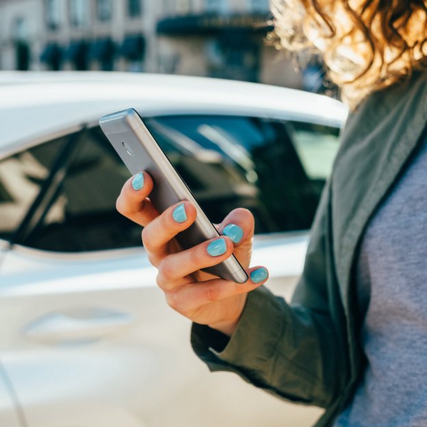 Eine Frau hält ein Smartphone in der Hand. | TÜVIT