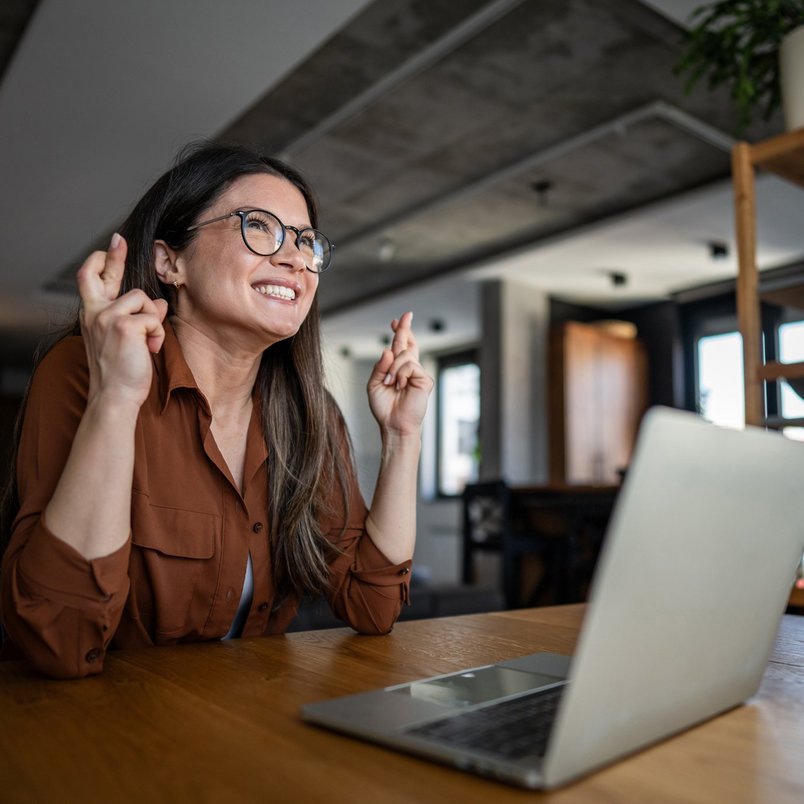 A woman crosses her fingers, hoping for luck in a contest on her laptop