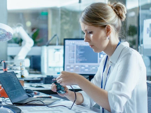 A woman works at a desk in a hardware laboratory.