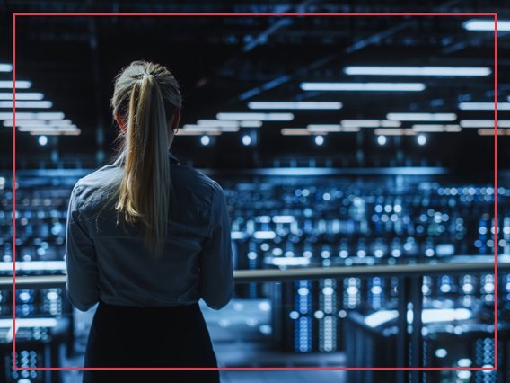 it-großraumbüro Eine Mitarbeitende steht in einem abgedunkelten IT-Großraumbüro