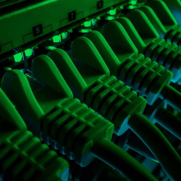 Server Rack mit gepatchten Datenkabeln und grün leuchtenden Dioden