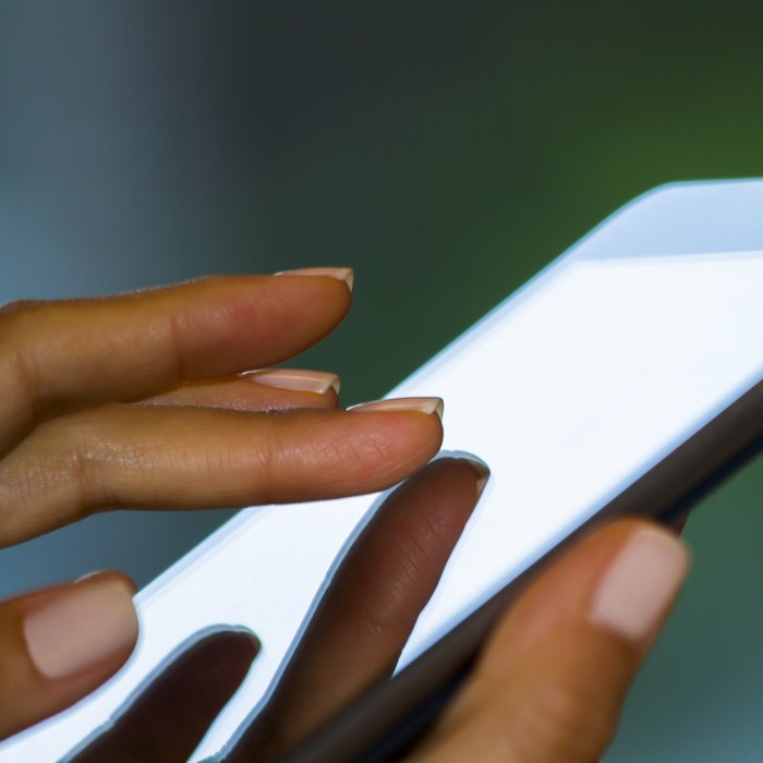 Die Hand einer Frau bedient die Oberfläche einer Mobilen Anwendung auf einem Smartphone