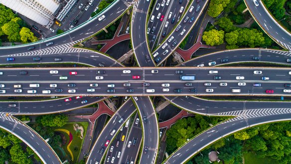 Autobahnkreuz mit vielen Fahrzeugen von oben fotografiert. | TÜVIT