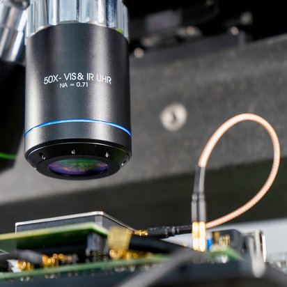 hardware-labor-laser-faultinjection-objektivlinse Lasergestützte Faultinjection (LFI) eines Samsung Mobile Chips. Die Objektivlinse der Laseroptik fokussiert den Laserstrahl direkt auf die Schaltstrukturen des Chips.