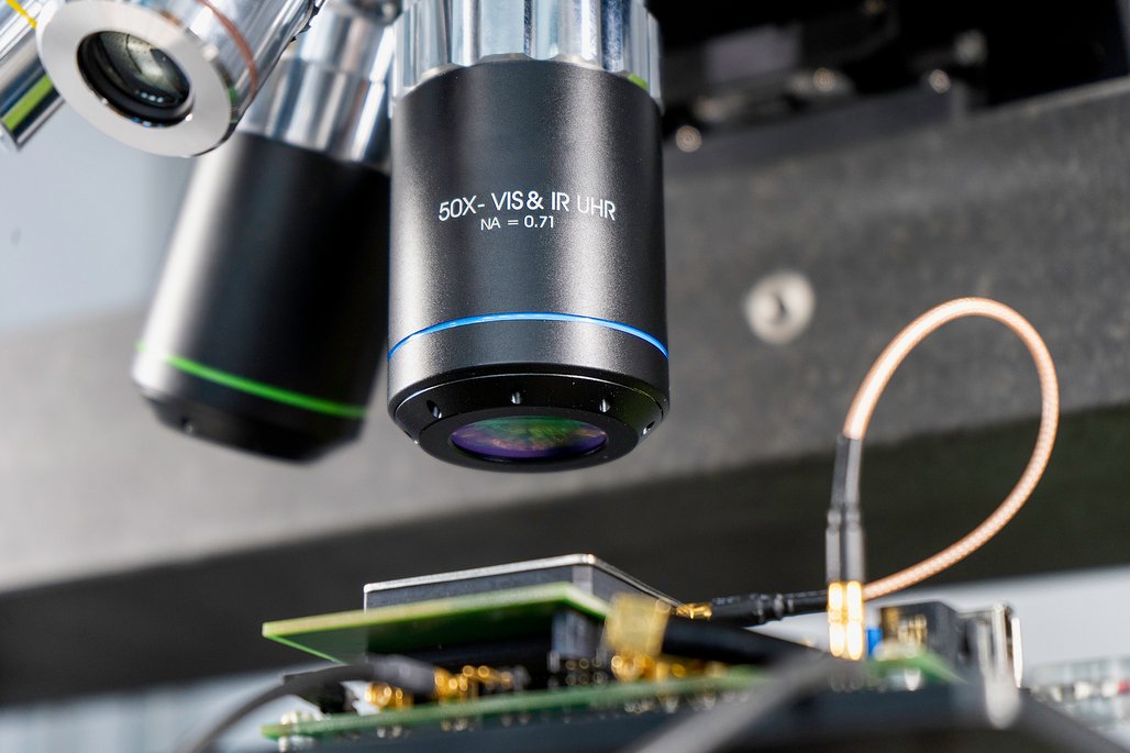 Lasergestützte Faultinjection (LFI) eines Samsung Mobile Chips. Die Objektivlinse der Laseroptik fokussiert den Laserstrahl direkt auf die Schaltstrukturen des Chips.