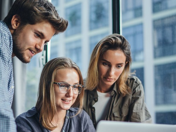 Three people look at a screen together.