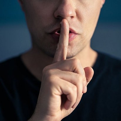 Zeigefinger als Zeichen für Ruhe Eine Person signalisiert mit dem Zeigfinger am Mund Ruhe.