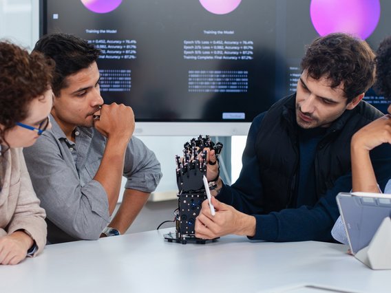 Employees at a startup are brainstorming together about a bionic robotic hand equipped with AI.