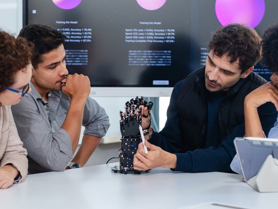 Employees at a startup are brainstorming together about a bionic robotic hand equipped with AI.