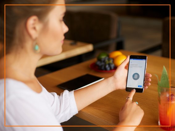 fingerabdruck-smartphone-identität-verifizierung Eine Frau verifiziert ihre Identität am Smartphone via Fingerabdruck.