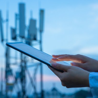 Tablet mit Funktmast im Hintergrund.